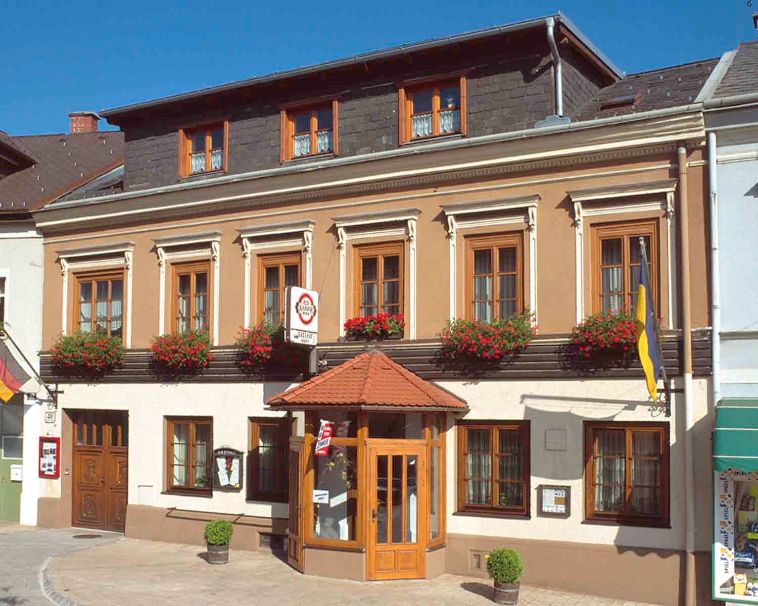 Tradičný hostinec s kvetmi a vlajkami.