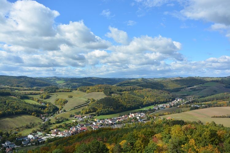 Krajina s kopcami, lesmi a dedinou na jeseň.