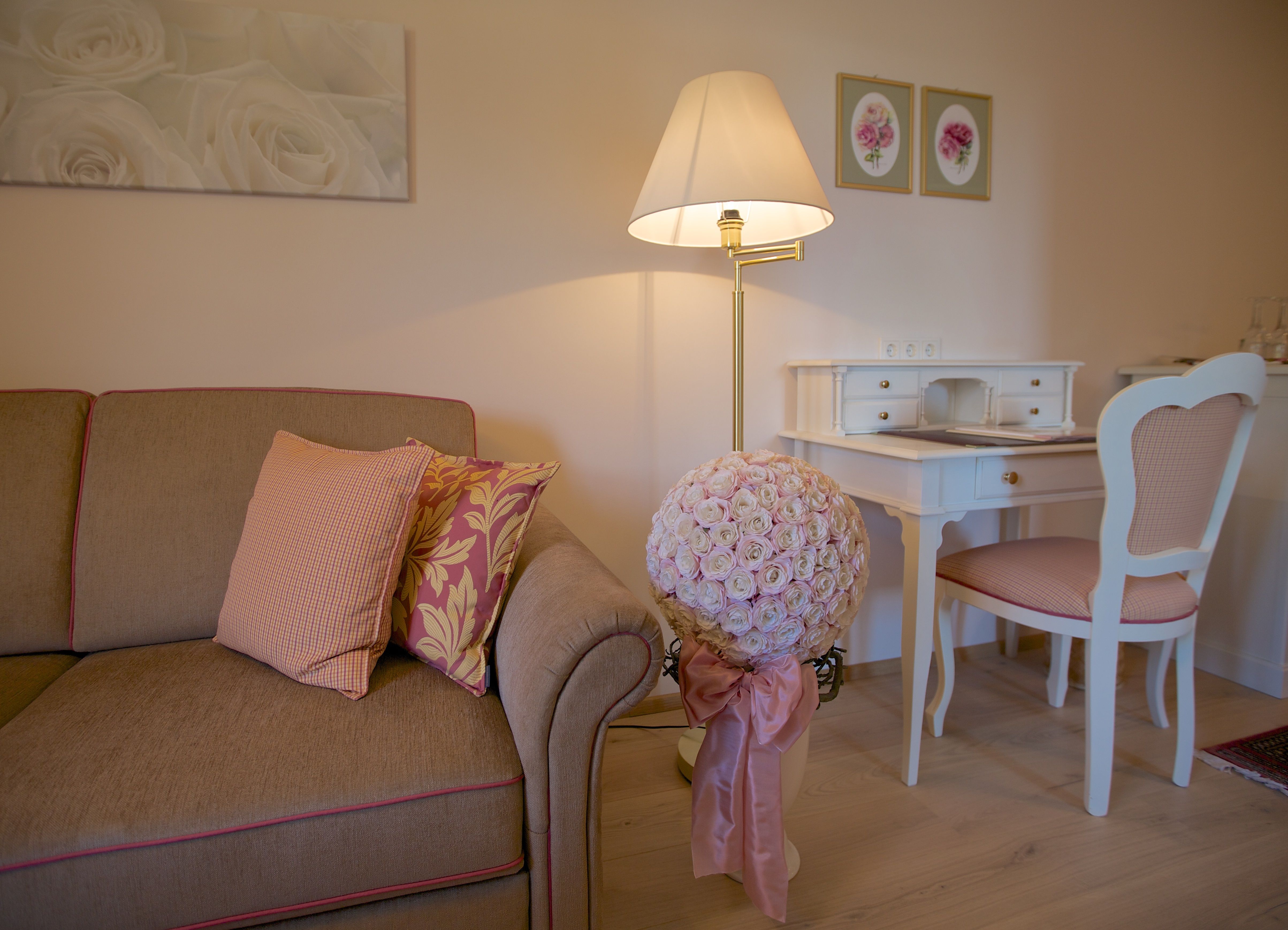 Útulná obývacia izba s pohovkou, písacím stolom a kvetinovou výzdobou.