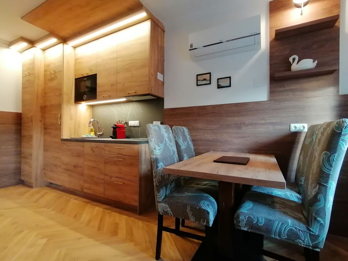 Moderná kuchyňa s dreveným nábytkom a jedálenským stolom v byte.