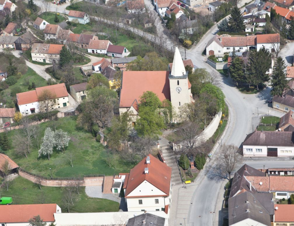 Letecký pohľad na kostol v dedine s okolitými domami a ulicami.
