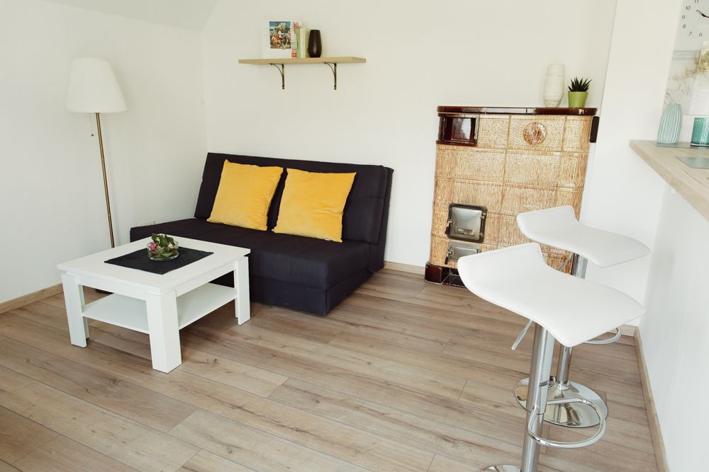 Moderná obývacia izba s pohovkou, konferenčným stolíkom, barovými stoličkami a krbom.