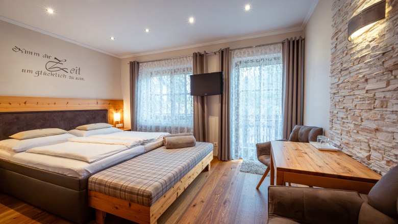 &Uacute;tuln&aacute; sp&aacute;lňa s manželskou posteľou, dreven&yacute;m n&aacute;bytkom a kamennou stenou.