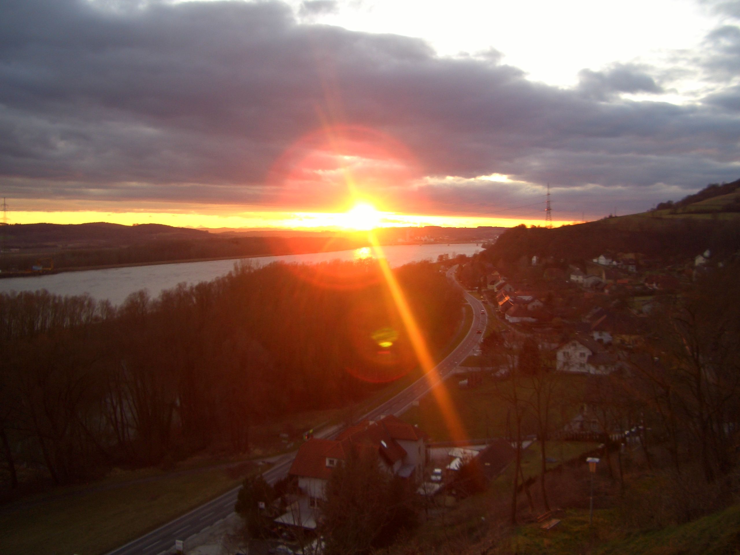 Západ slnka nad krajinou s riekou a cestou.