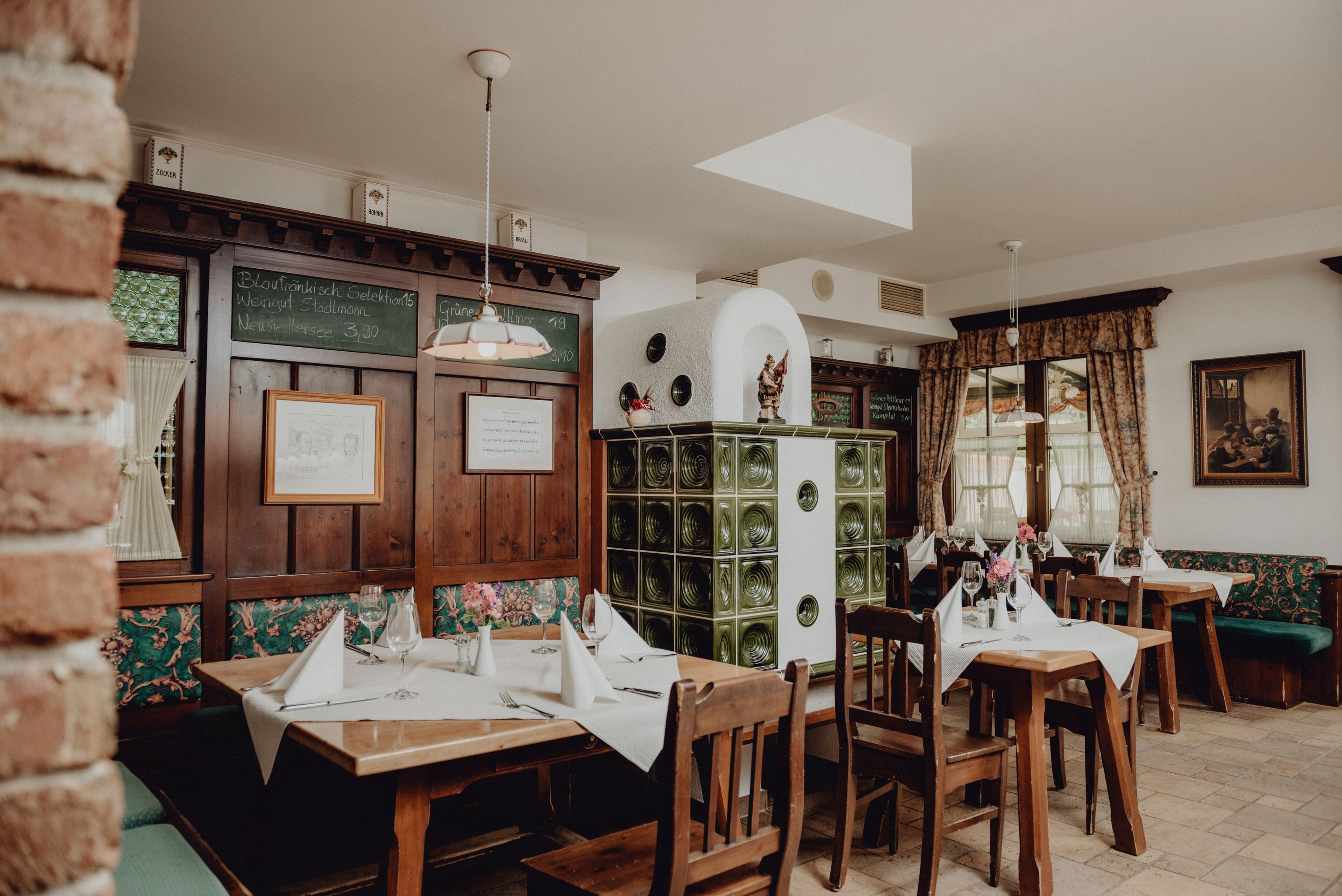 Útulná reštaurácia s dreveným nábytkom, kachľovou pecou a zdobenými stolmi.