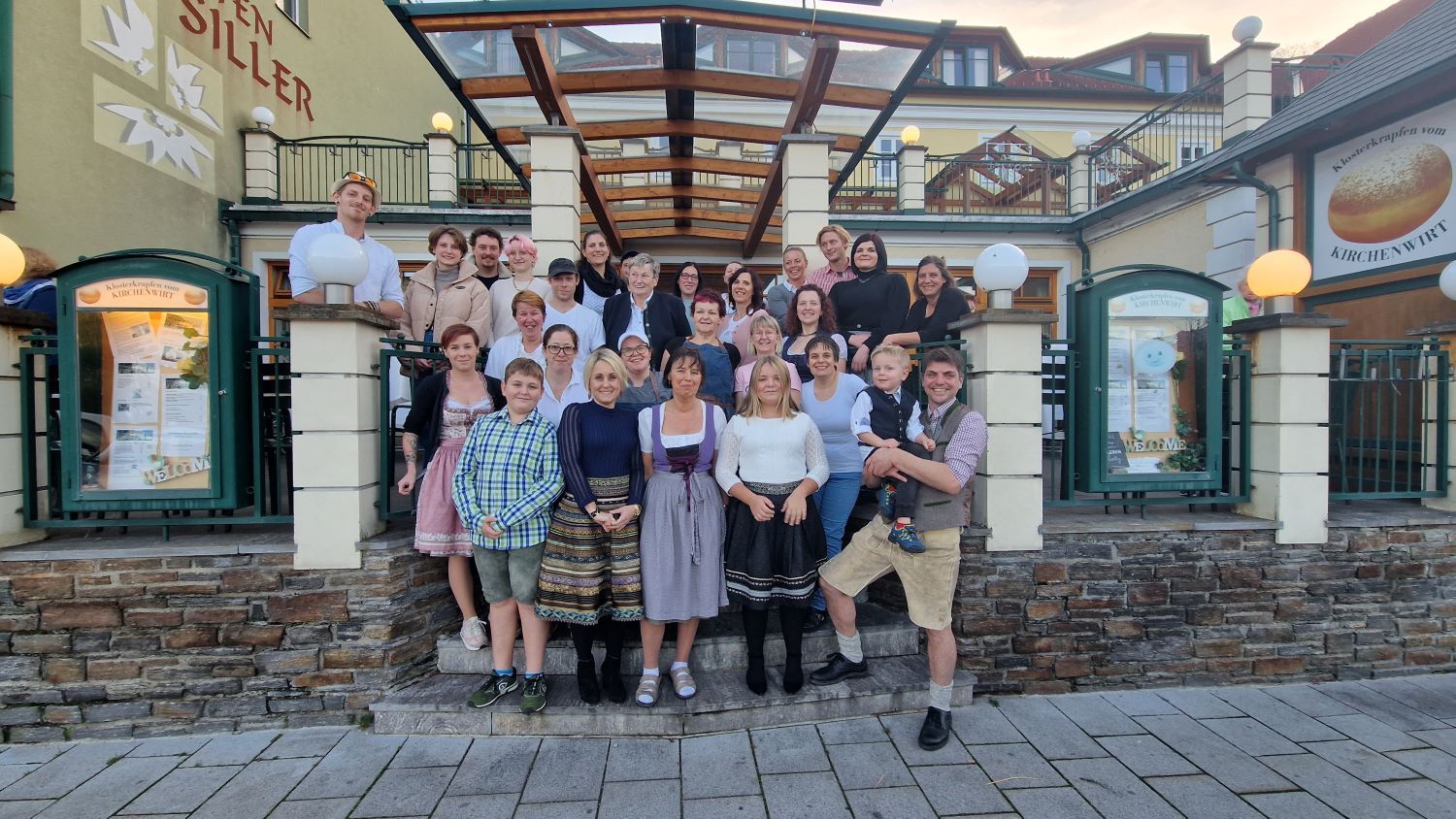 Skupina ľudí stojí pred budovou s nápisom Kirchenwirt.