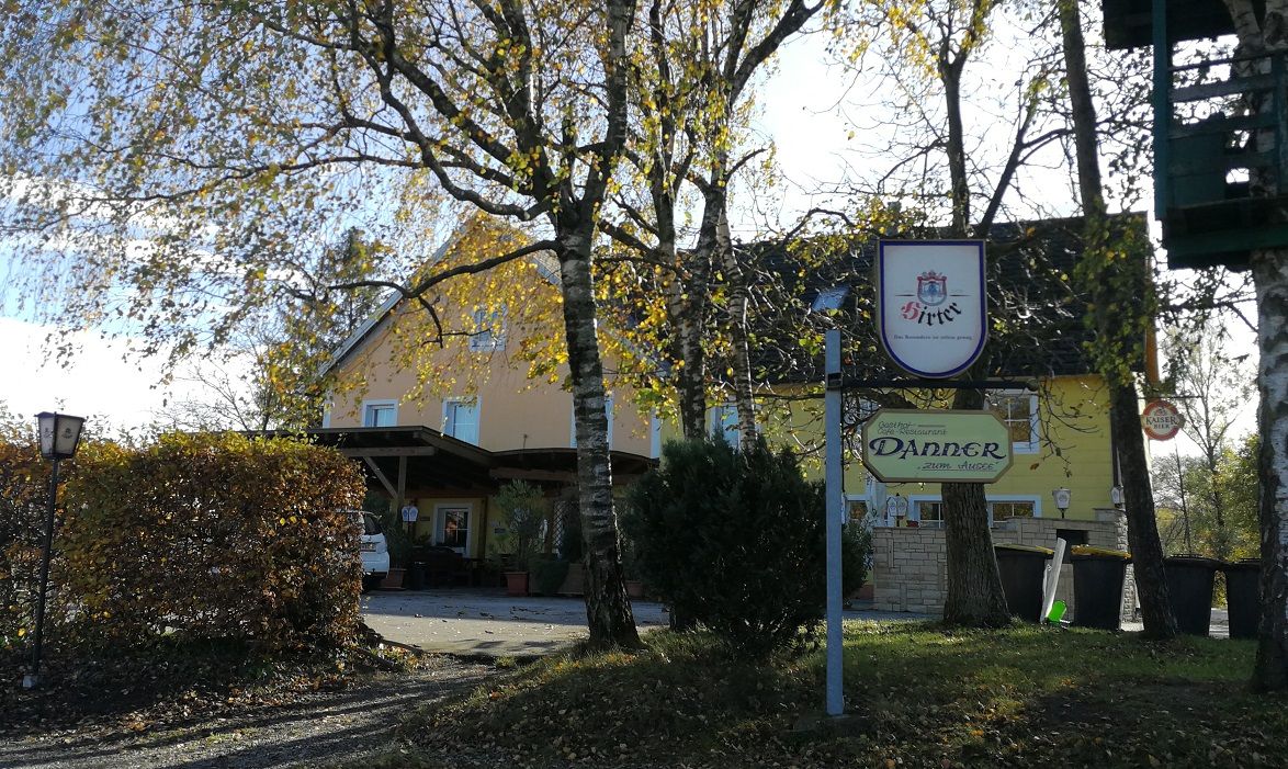 Gasthaus Danner so stromami v popredí a nápisom.