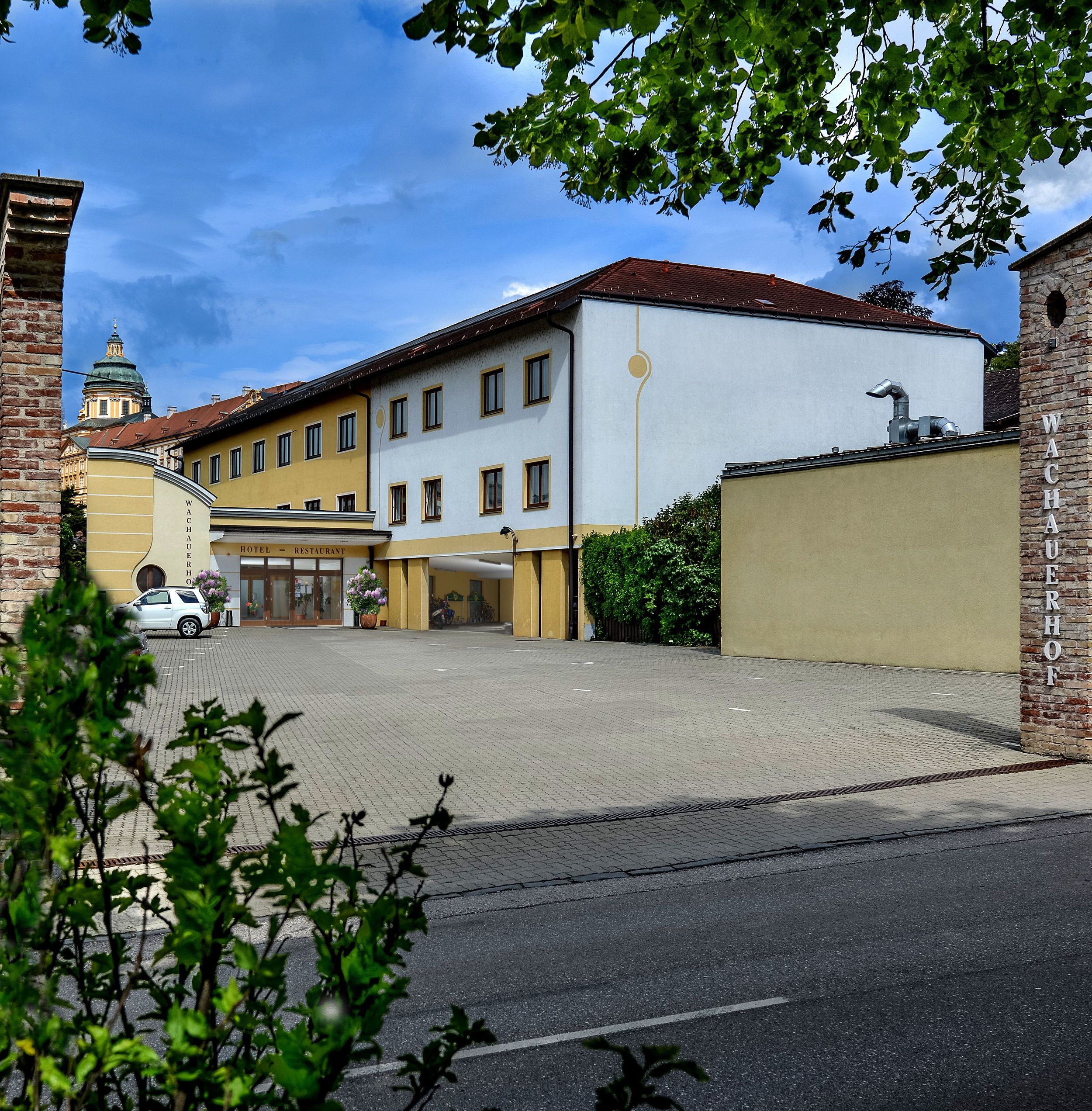 Exteriérový pohľad na Wachauerhof v Melku s parkoviskom a fasádou budovy.