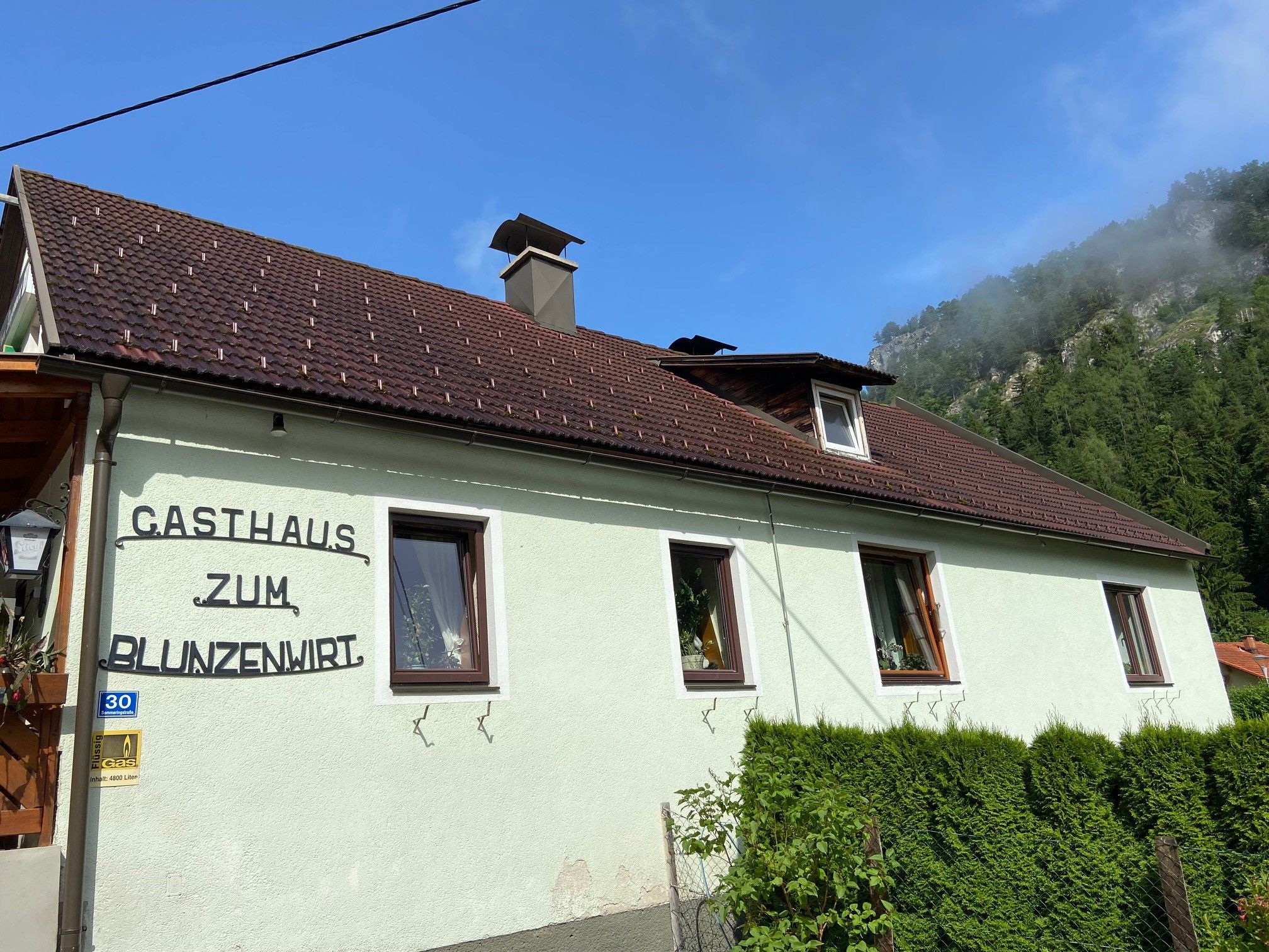 Exteriérový pohľad na hostinec Zum Blunzenwirt so zelenou farbou a hnedou strechou.