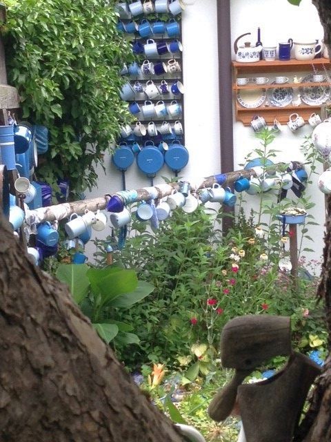 Záhrada s množstvom farebných pohárov zavesených na stenách a stĺpoch.