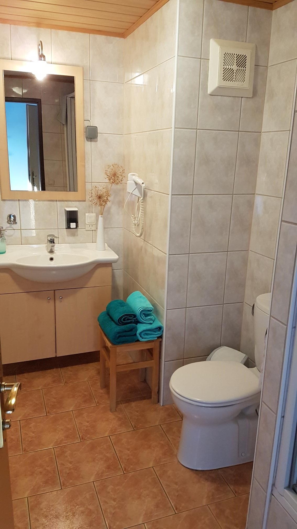 Kúpeľňa s umývadlom, zrkadlom, toaletou a uterákmi na stoličke.