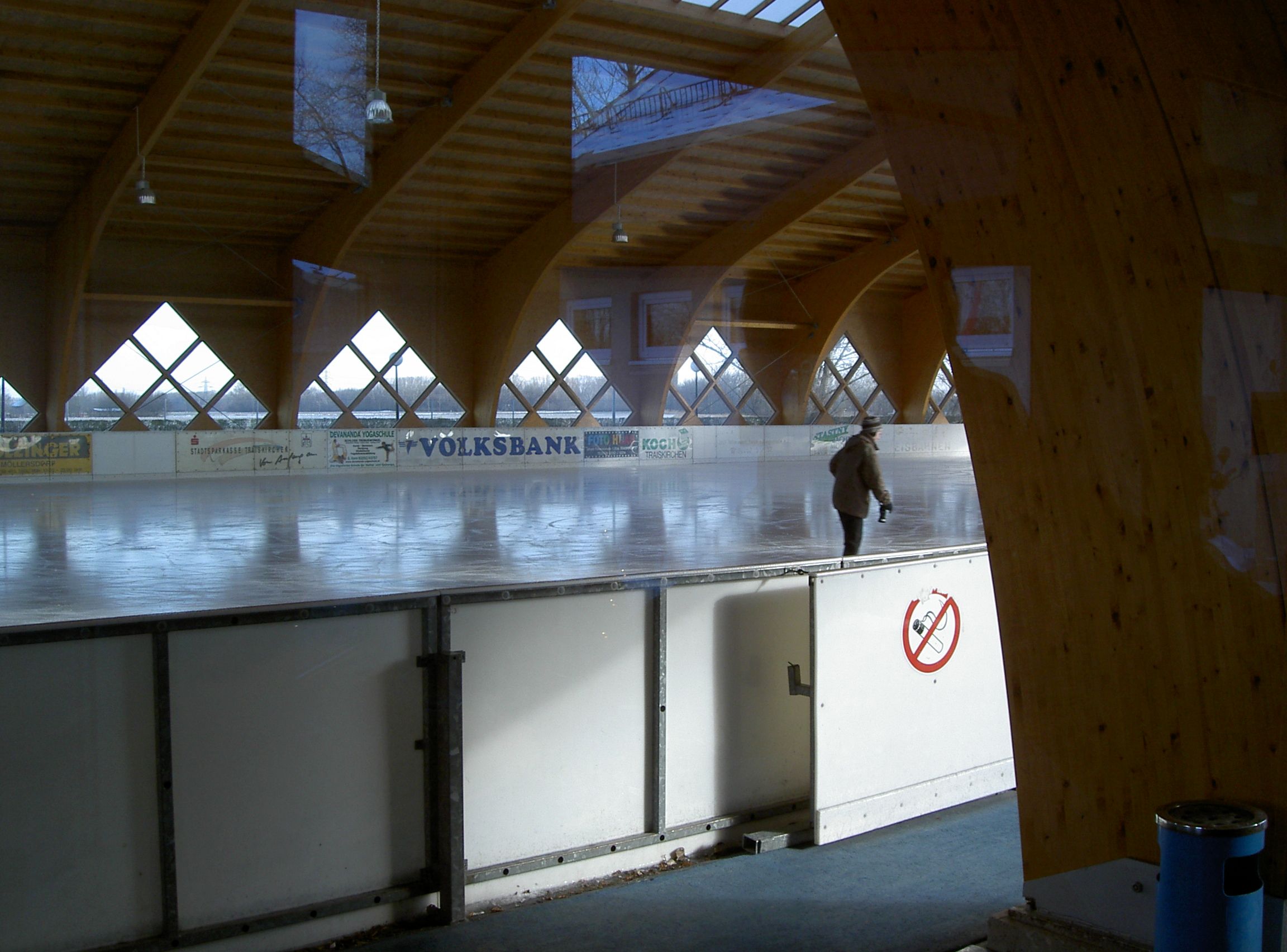 Kryté umelé klzisko, na ktorom korčuľuje človek. Klzisko je obklopené drevenými trámami a oknami.