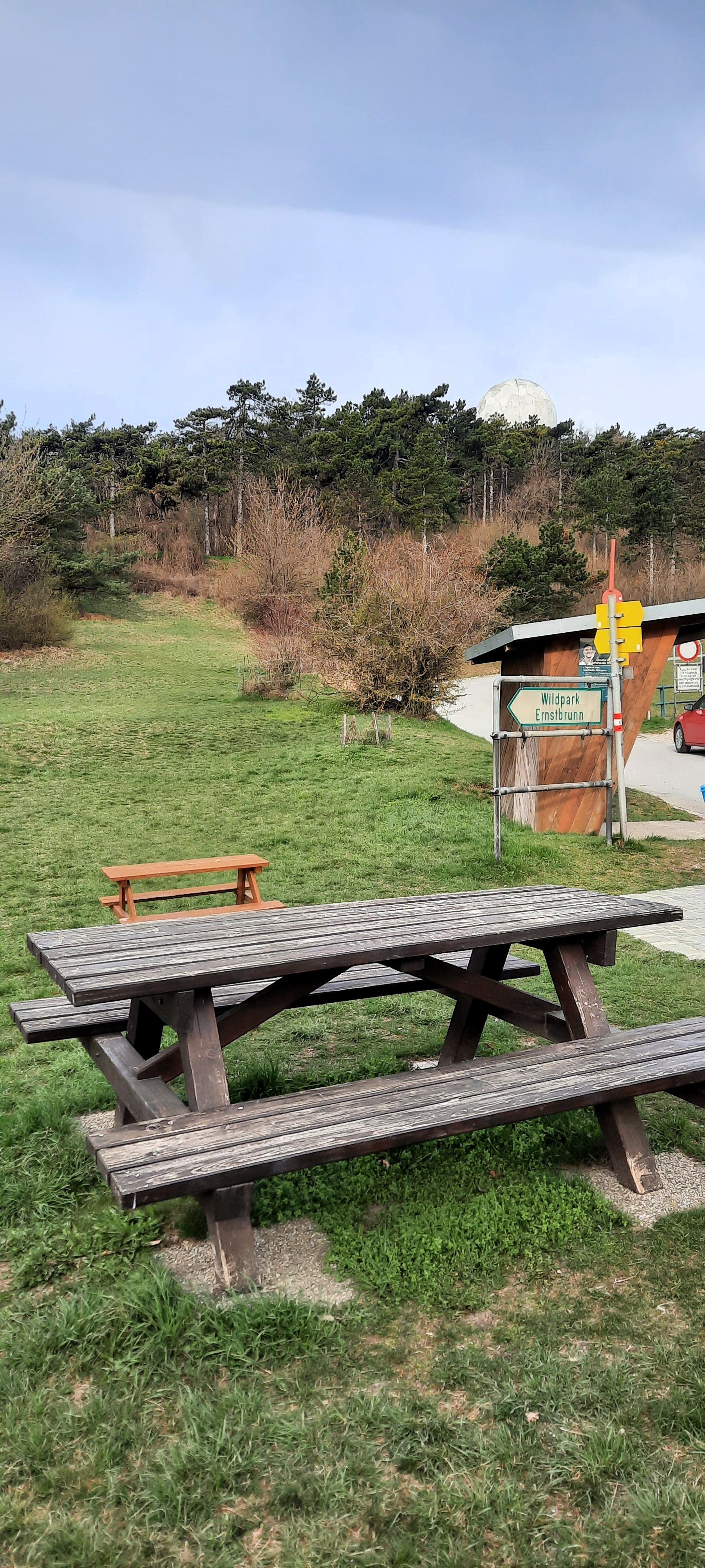 Piknikový stôl na lúke s lesom v pozadí a nápisom Ernstbrunn Wildlife Park.