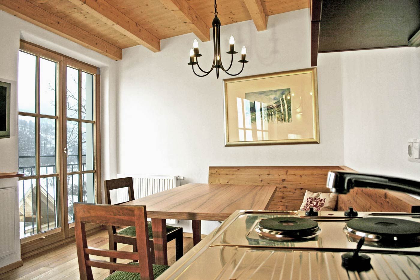 Útulná izba pre hostí s dreveným nábytkom a kuchynským kútom.