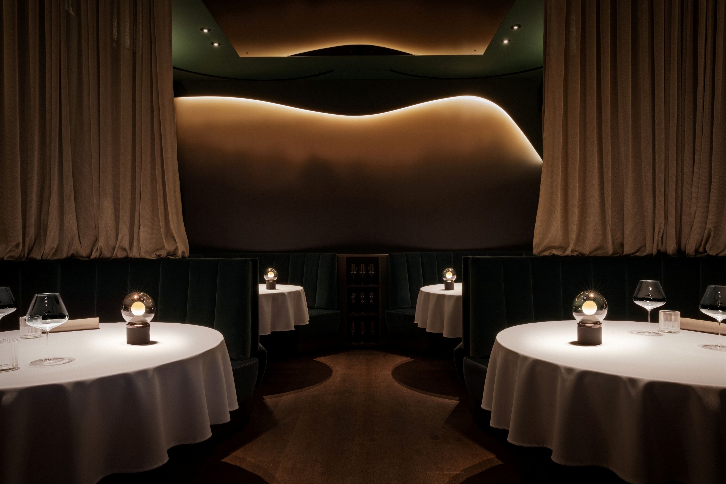 Elegantná reštaurácia s okrúhlymi stolmi, bielymi obrusmi a tlmeným osvetlením.