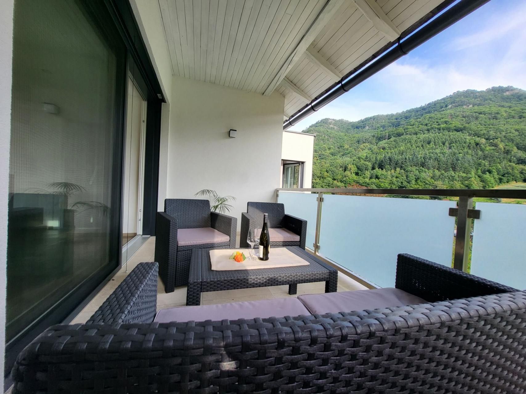 Balkón s ratanovým nábytkom a výhľadom na hory.