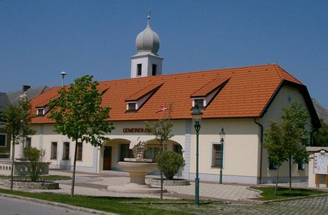 Obecný úrad v Göttlesbrunn-Arbesthal s červenou strechou a vežou.