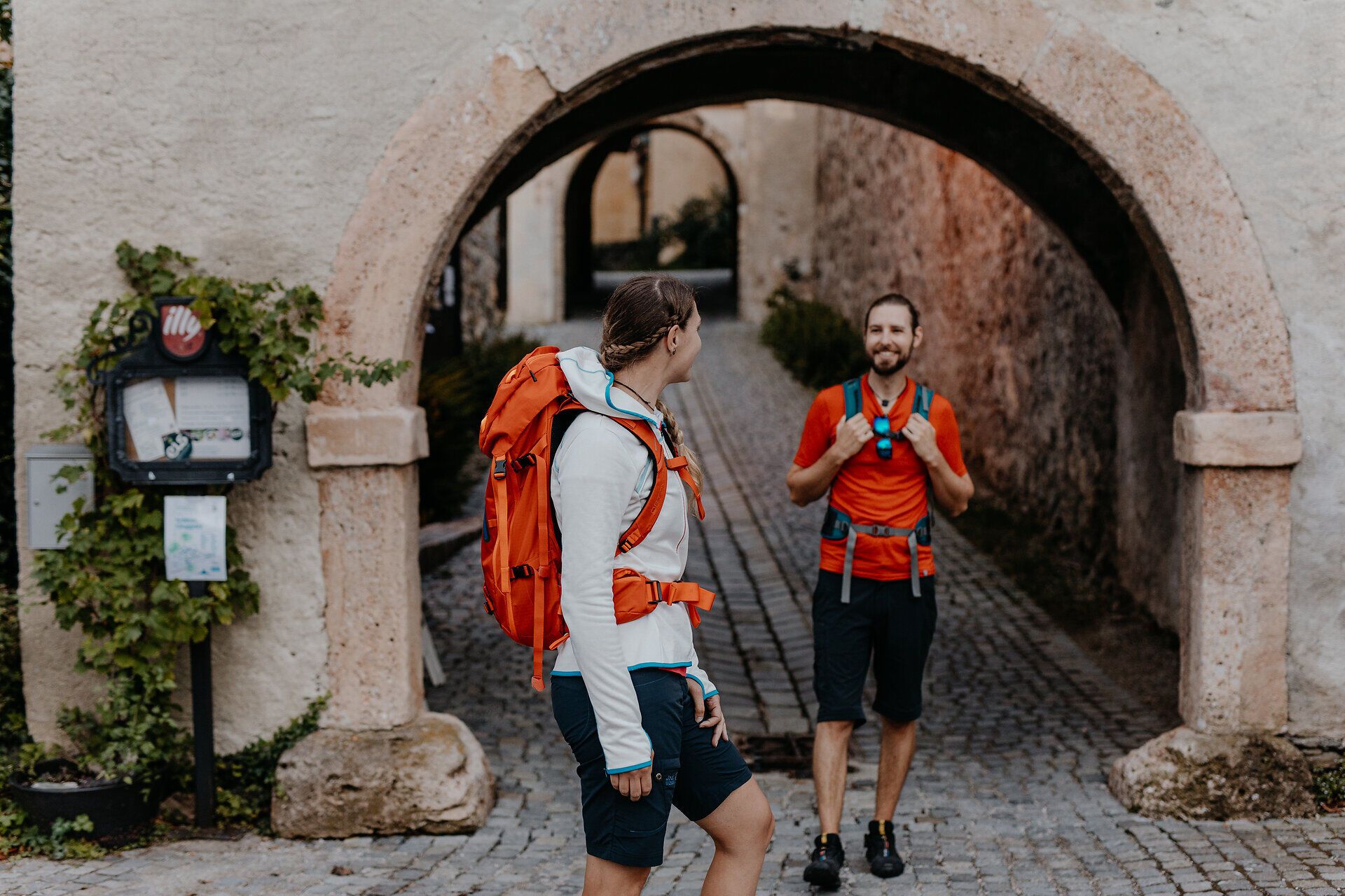 Dvaja turisti stoja pri vstupnej bráne do hradu Gloggnitz