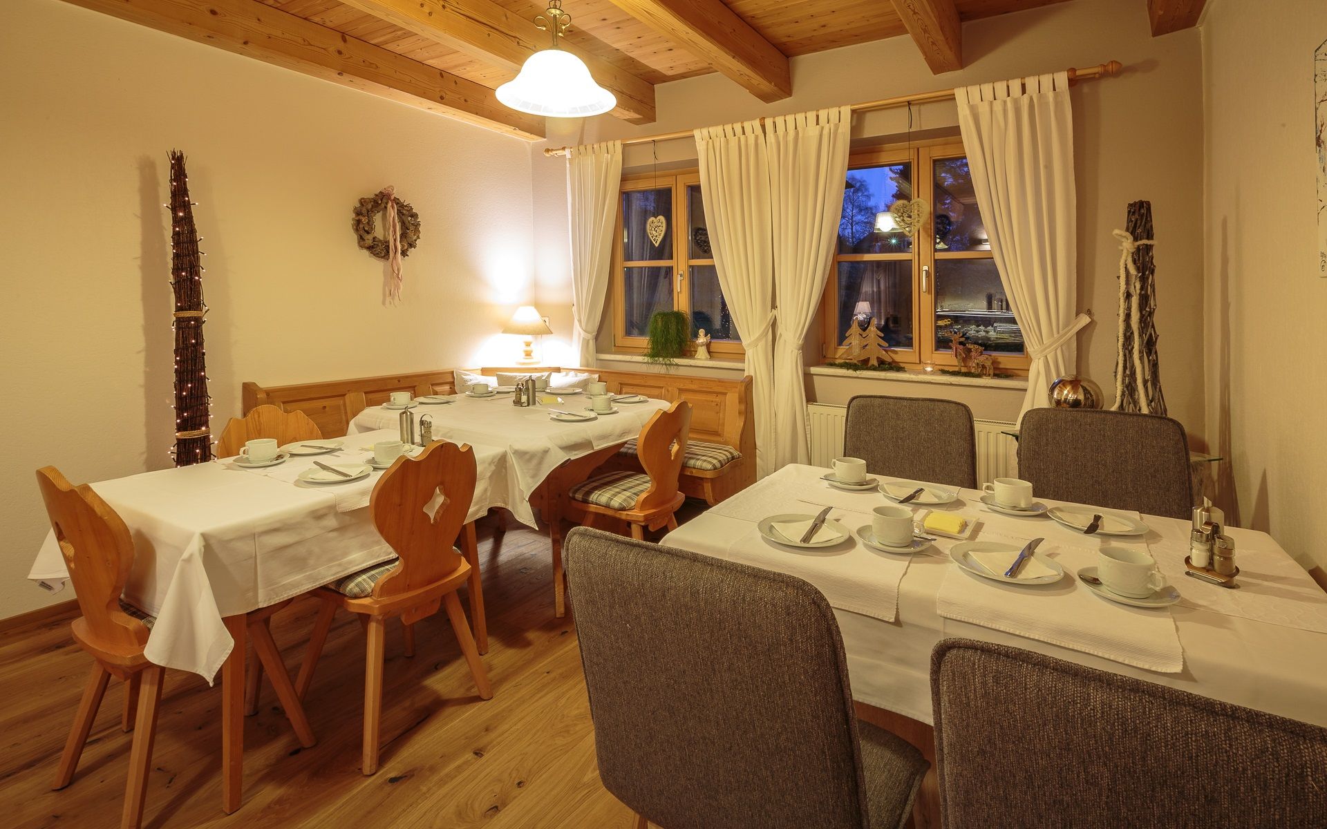 Útulná raňajková miestnosť s prestretými stolmi, dreveným nábytkom a dekoráciami.