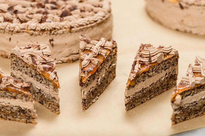 Detailný záber na nakrájané kúsky čokoládovej torty s krémom a čokoládovou polevou.