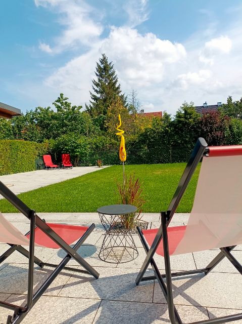 Dve ležadlá v záhrade s trávnikom a stromami v pozadí.