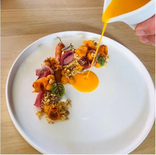 Detail pripravovaného pokrmu s čerstvými surovinami; vysokokvalitná prezentácia v prostredí modernej reštaurácie.