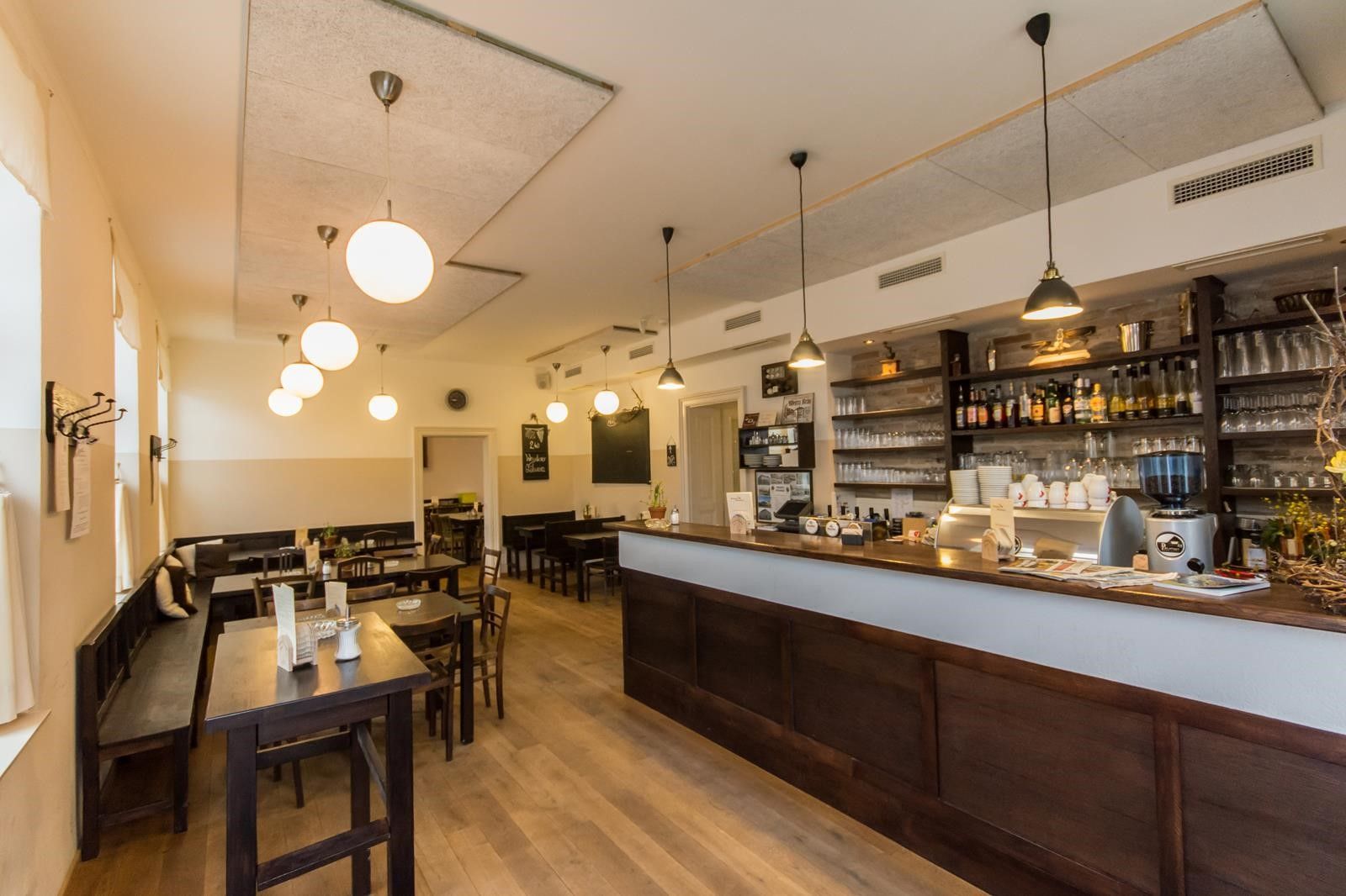 Pohľad do interiéru útulnej krčmy s dreveným nábytkom a barom.