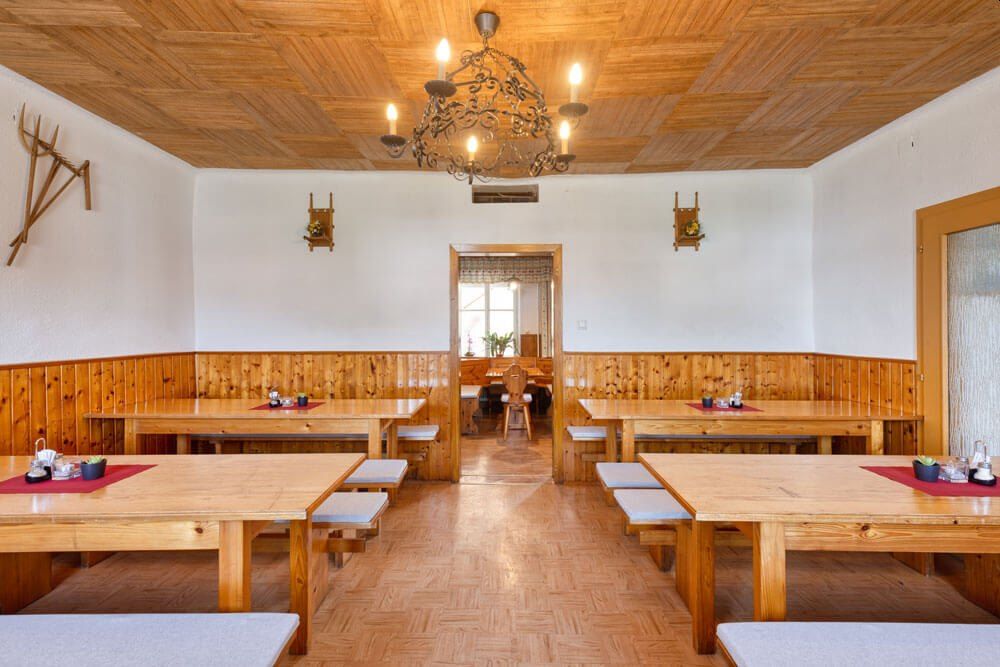 Pohľad do interiéru tradičnej vinárne s drevenými stolmi a lavicami, dreveným obložením stien a lustrom na strope.