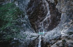 Ein erfrischender Wasserfall stürzt über die Felsen und schafft eine magische Atmosphäre inmitten der unberührten Natur. Die umliegenden grünen Wiesen und die majestätischen Berge laden dazu ein, die Schönheit des Bergsommers zu genießen und die Seele baumeln zu lassen.