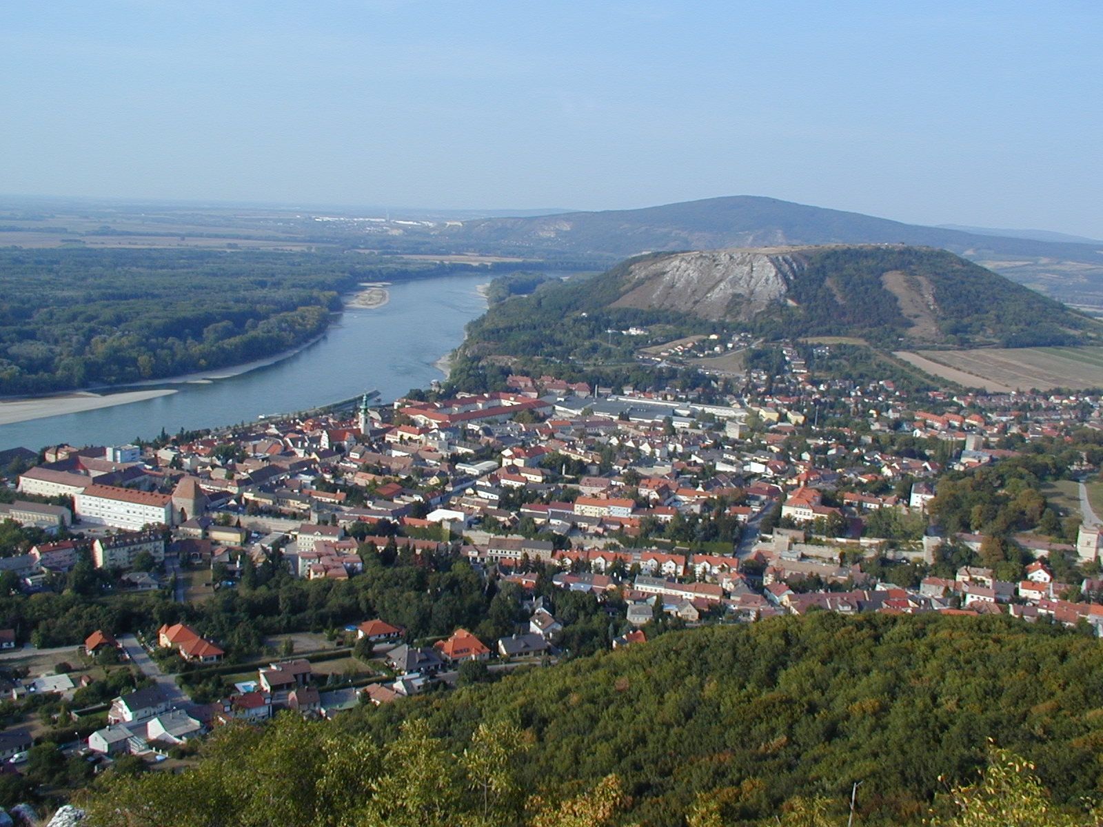 Panoramatický pohľad na mesto s riekou a kopcami v pozadí.