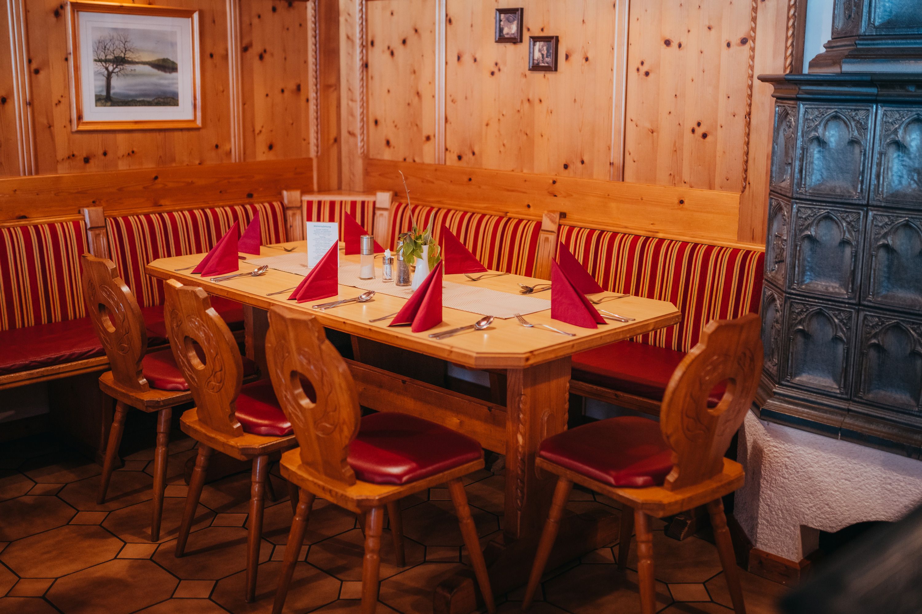 Útulný salónik s dreveným nábytkom, červeným čalúnením a kachľovou pecou.