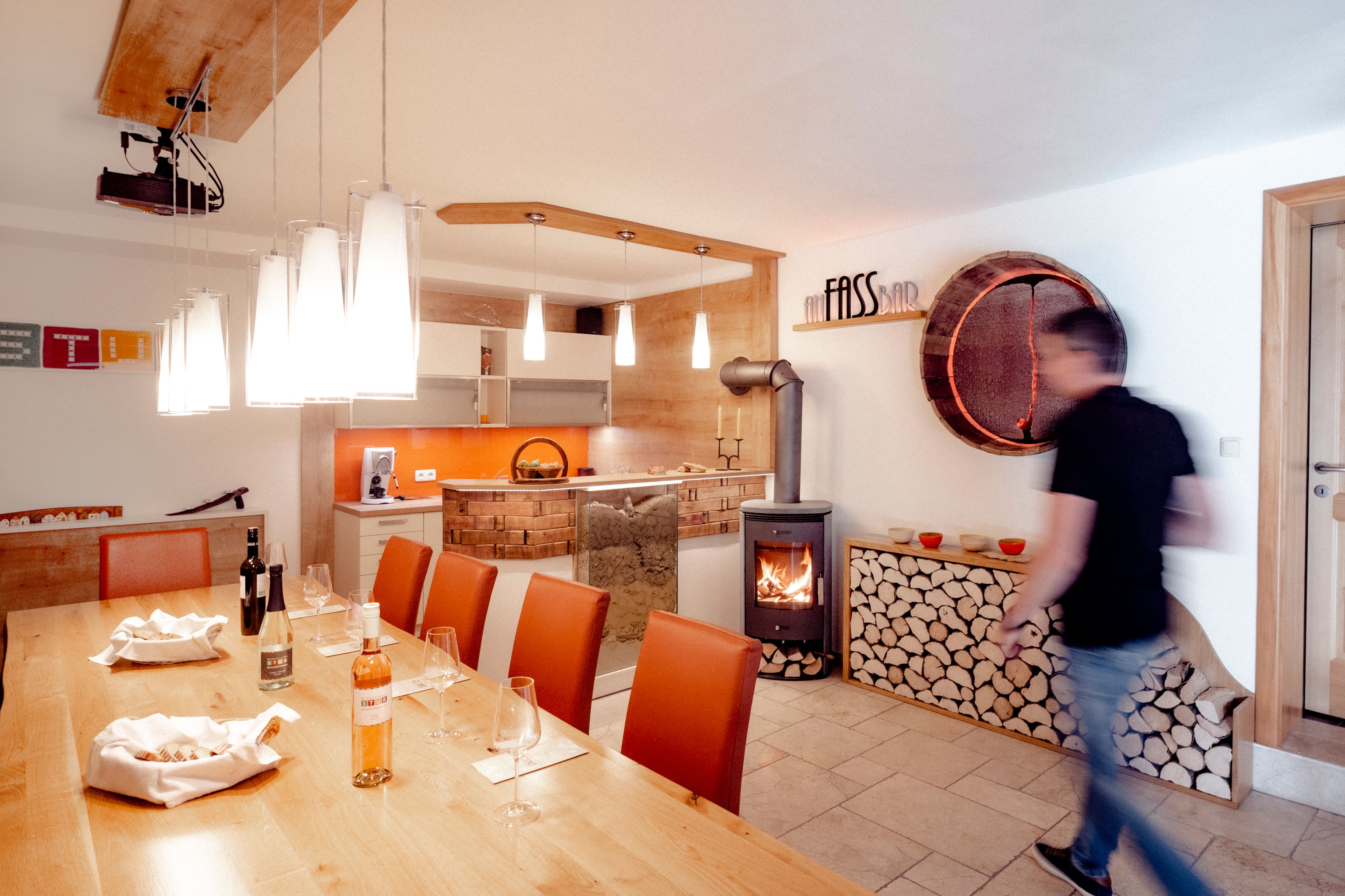 Degustačná miestnosť s dreveným stolom, pohármi na víno, krbom a moderným osvetlením.