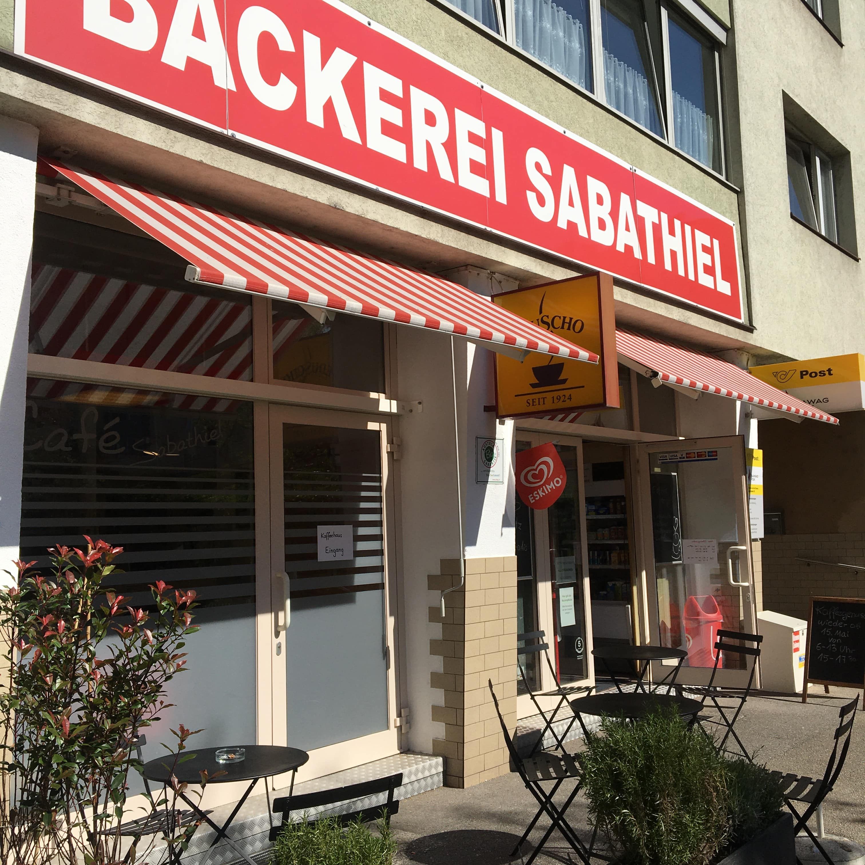 Exteriérový pohľad na pekáreň s červenými markízami a vonkajším sedením.