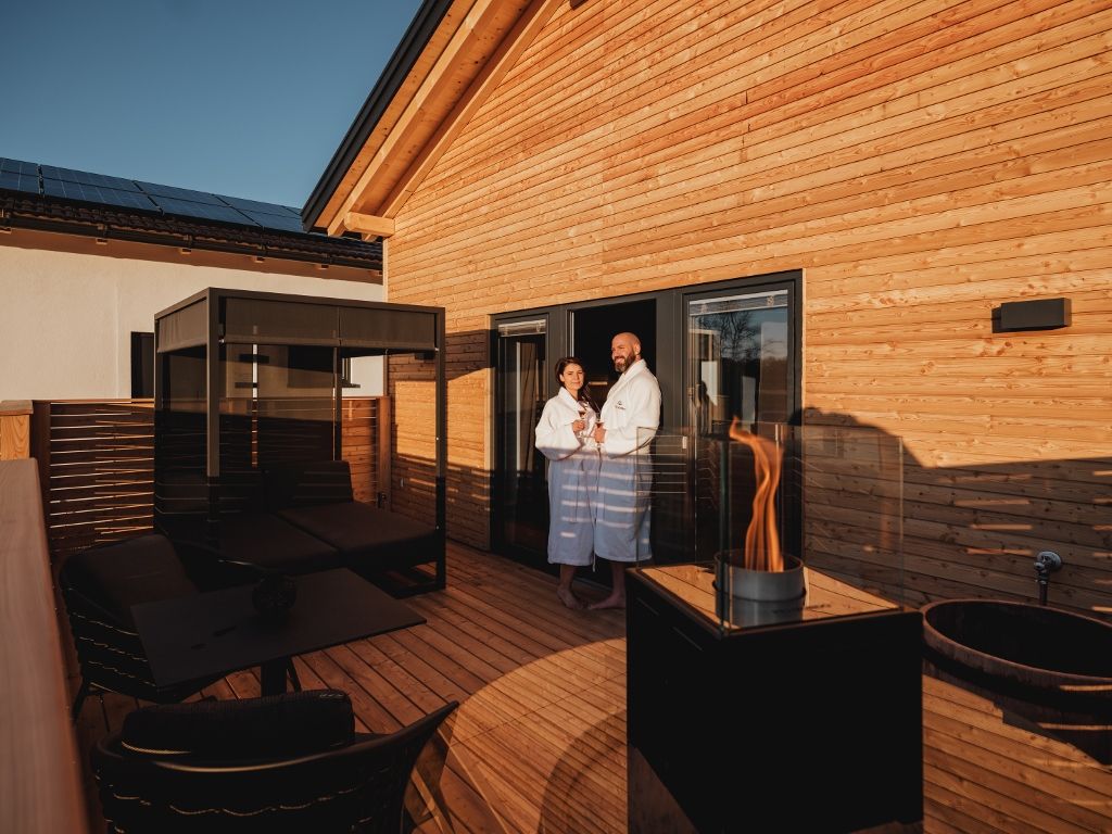 Terasa s posteľou s baldachýnom, krbom a dvoma osobami v županoch.