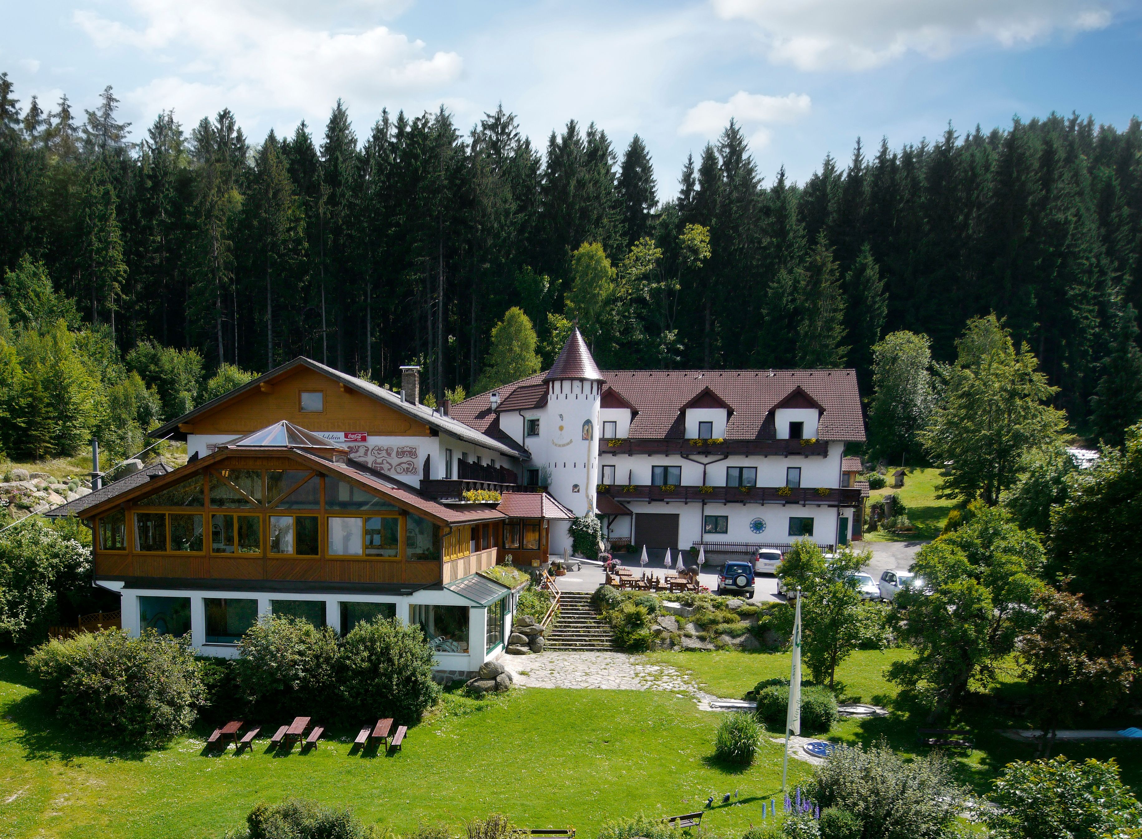 Hotel v lese s vežou a záhradou.