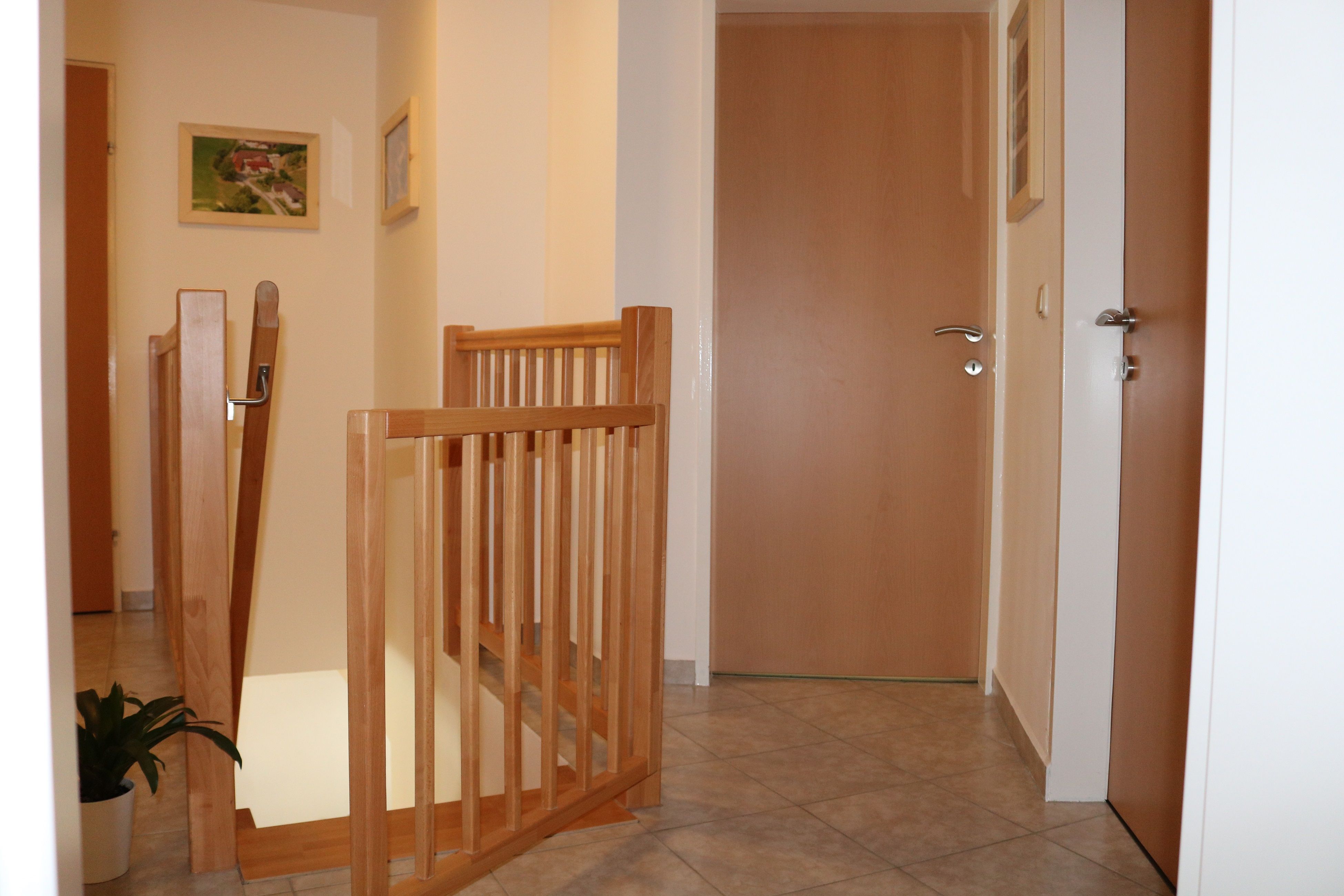 Pohľad do interiéru chodby s drevenými dverami a zábradlím.