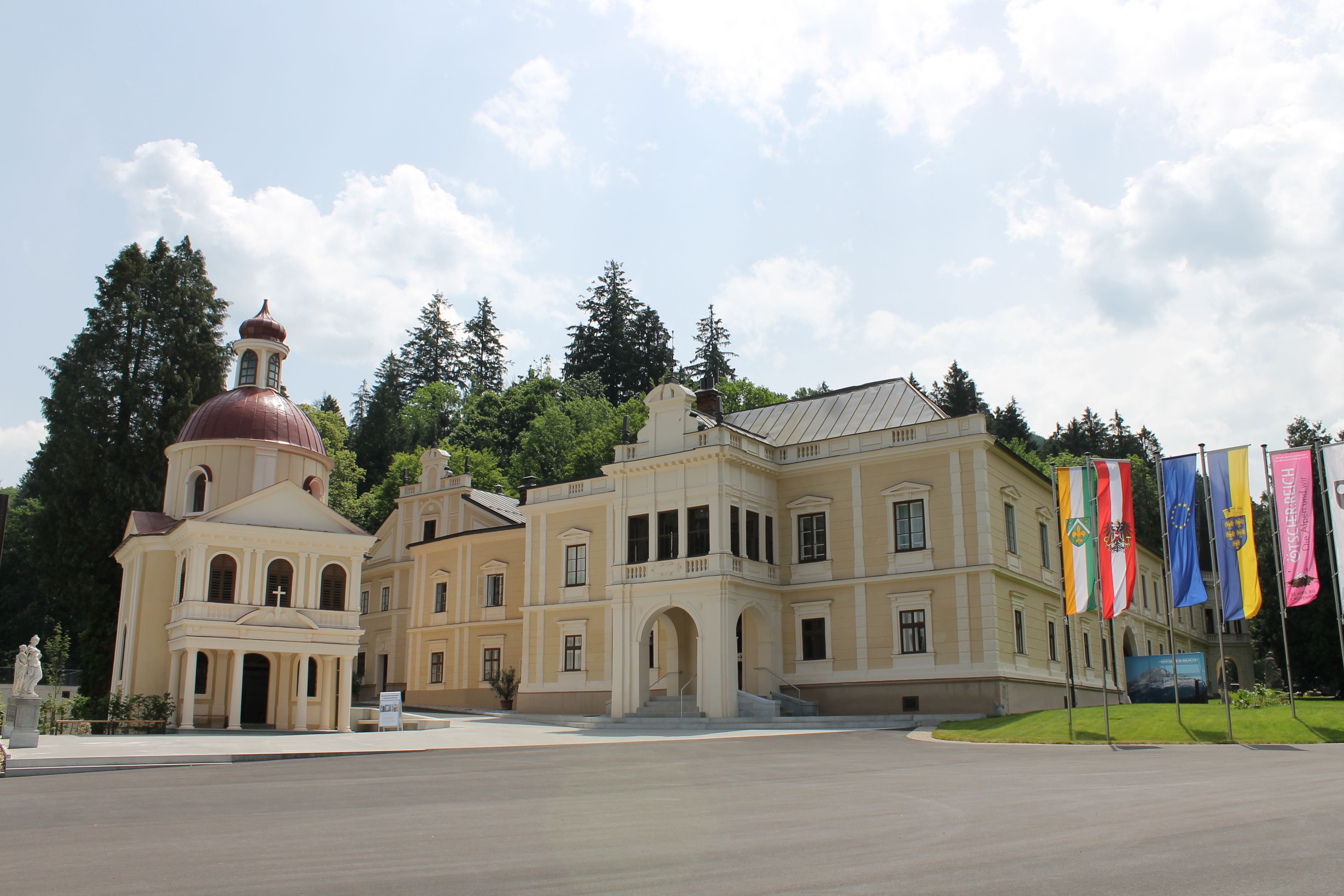 Hrad Neubruck s kaplnkou a vlajkami v popredí.