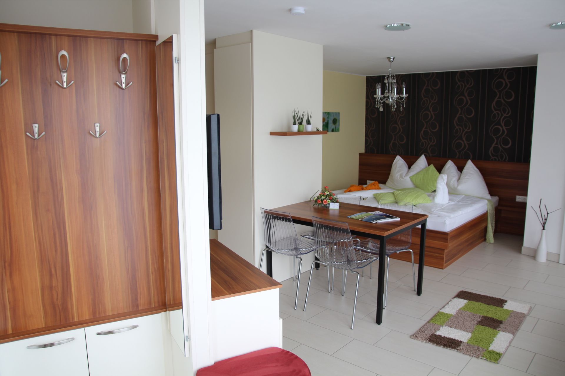 Moderný byt s dreveným nábytkom, jedálenským stolom, posteľou a dekoratívnymi prvkami.