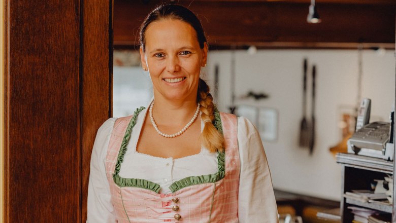 Žena v tradičnom kroji sa usmieva v reštaurácii.