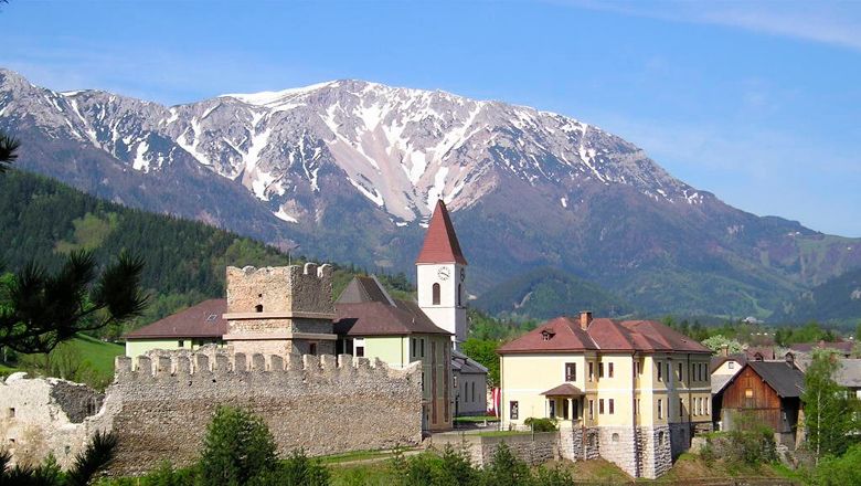 Zrúcaniny Puchbergu pred zasneženým horským masívom.