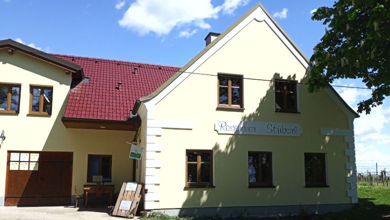 Žltá budova s červenou strechou a nápisom "Rosenauer Stüberl".