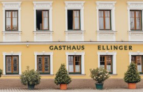 Fasáda žltého hostinca s nápisom "Gasthaus Ellinger".