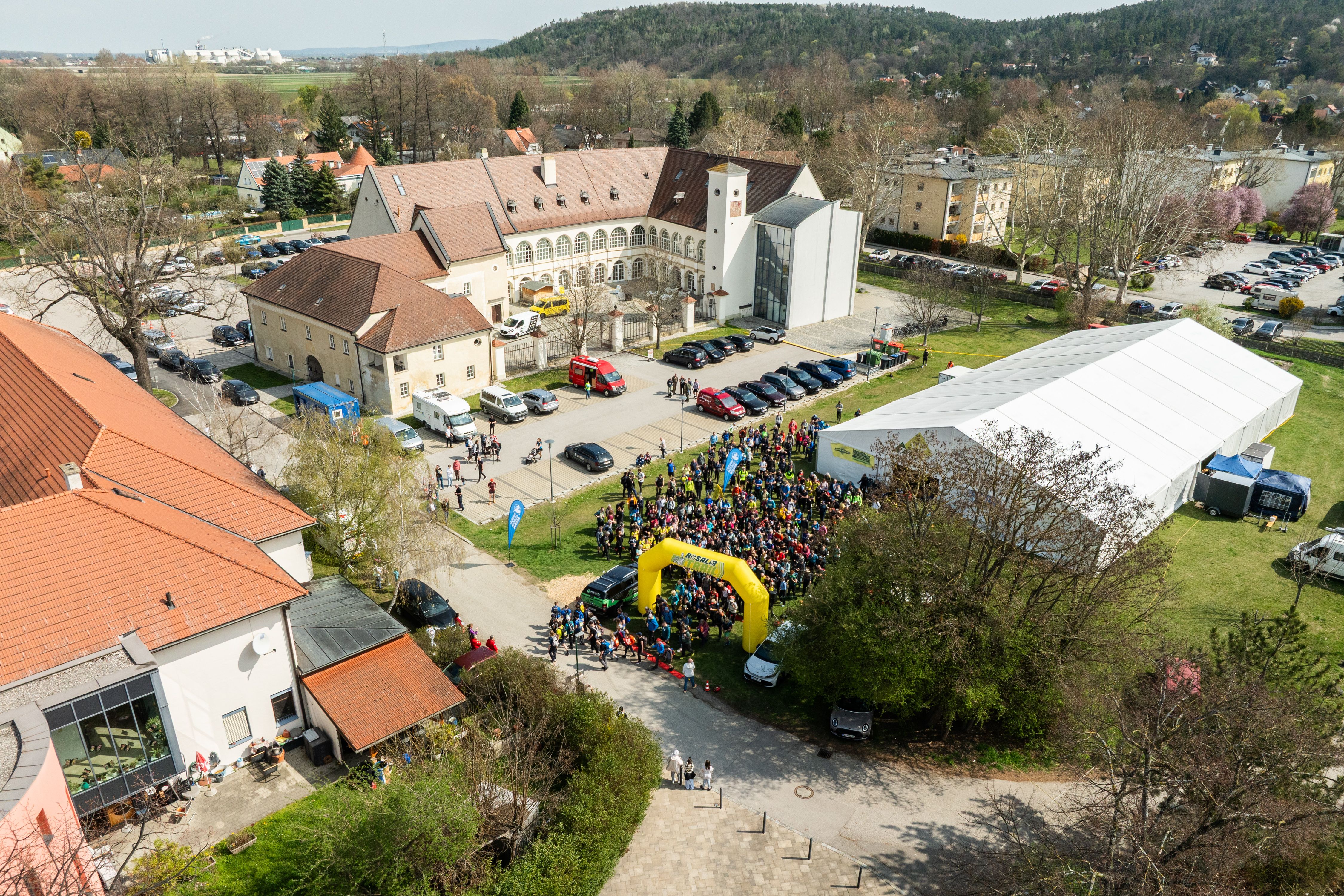Letecký pohľad na hrad s množstvom ľudí, stanov a budov počas podujatia Rosalia Trail Challenge.