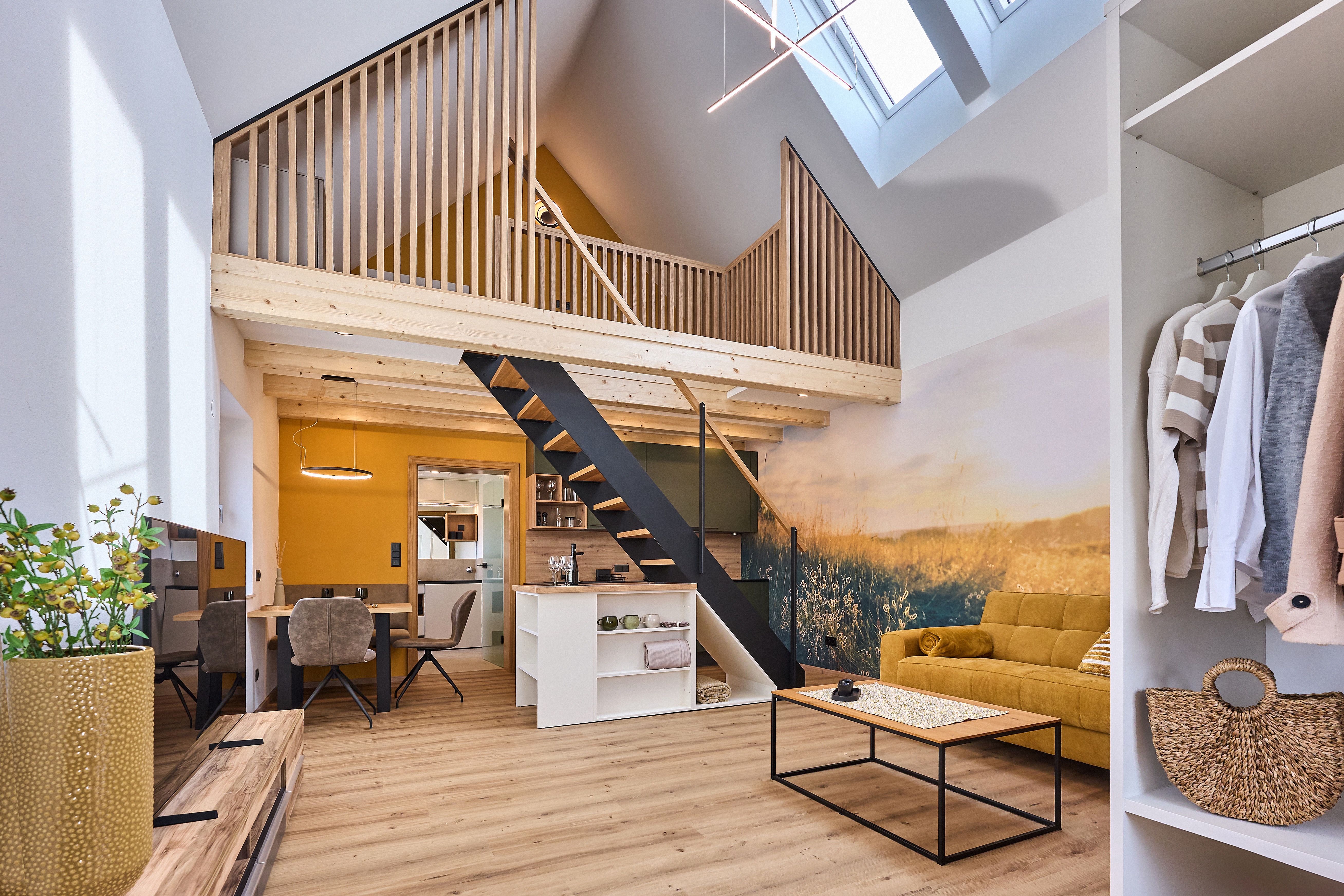 Moderný loft s otvorenou galériou, žltou pohovkou a drevenými prvkami.