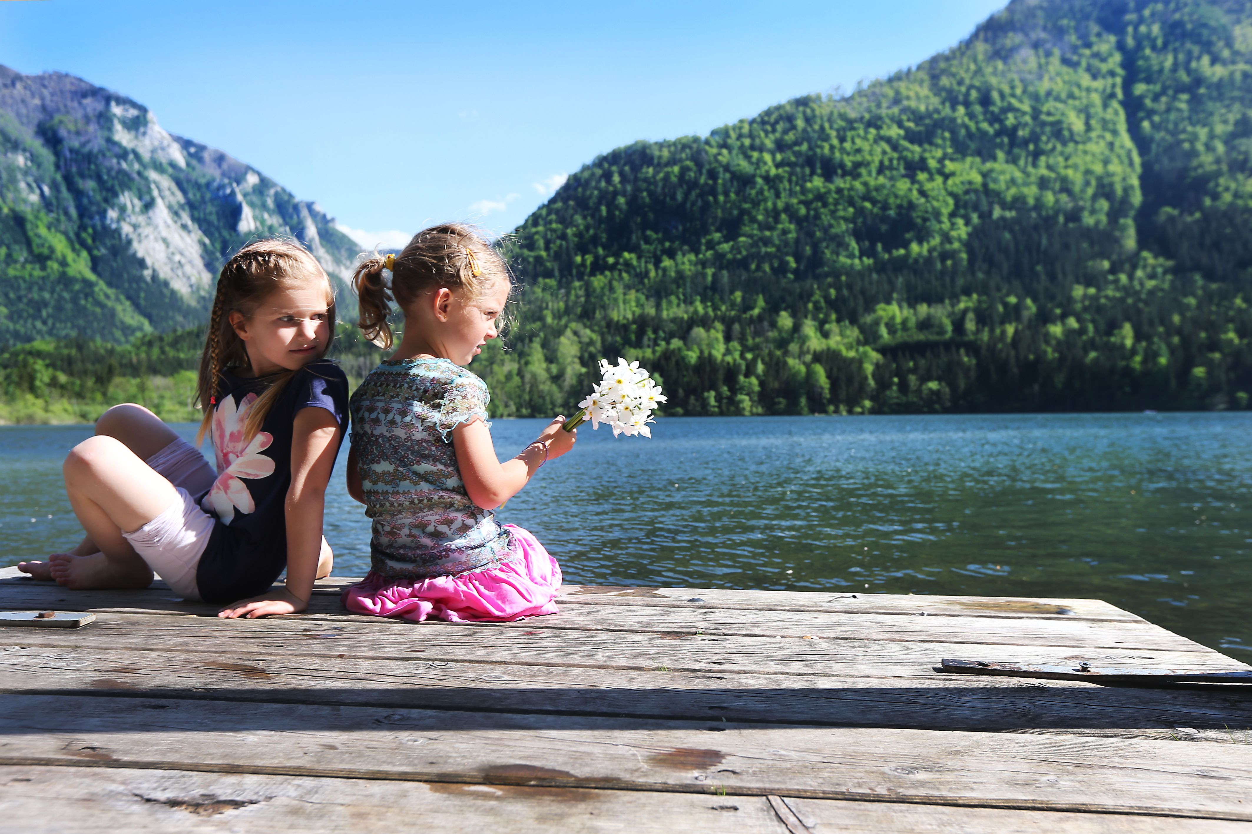Dve deti sedia na móle na Lunzersee s horami v pozadí.
