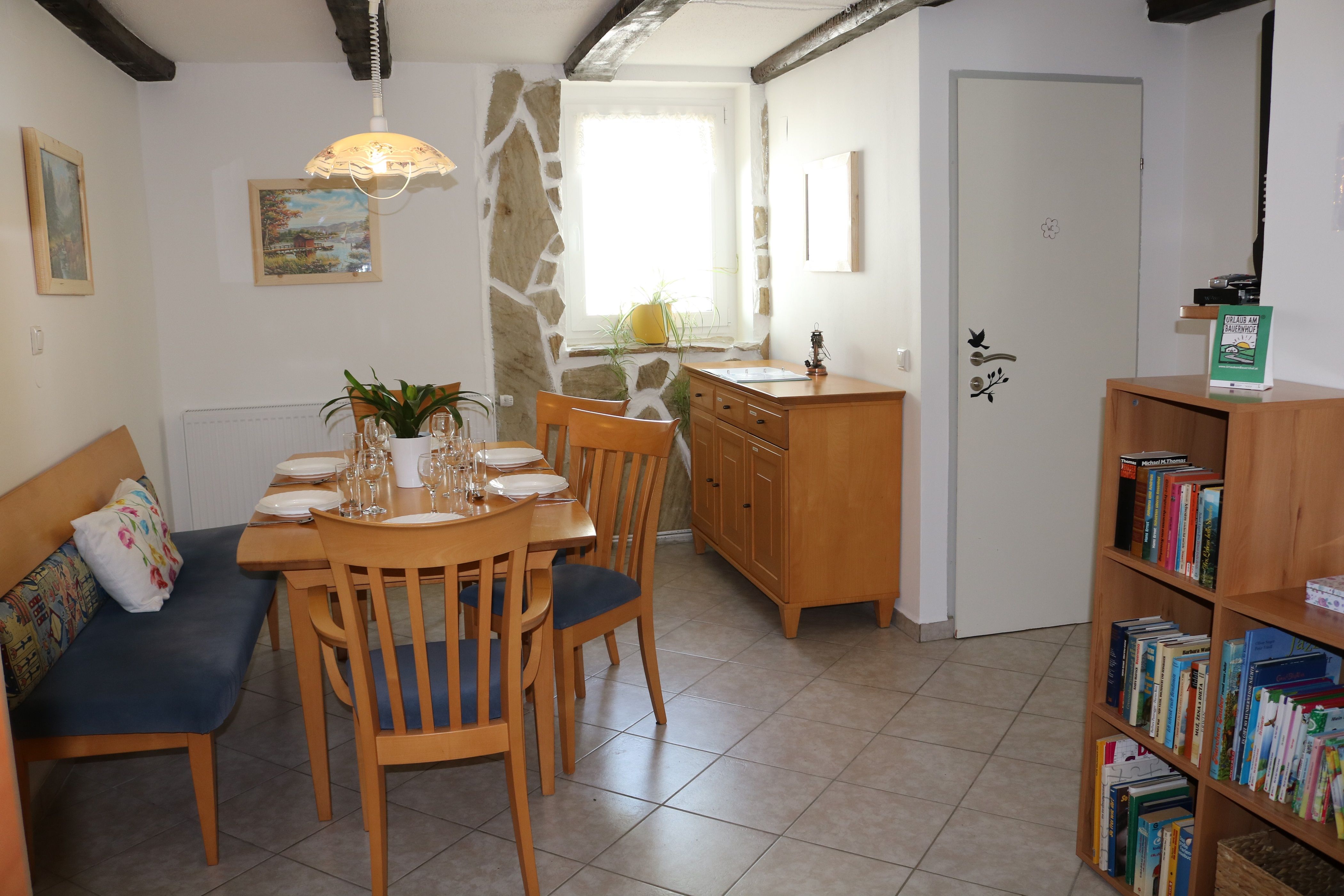 Jedálenský kút s dreveným stolom, stoličkami a policou na knihy.