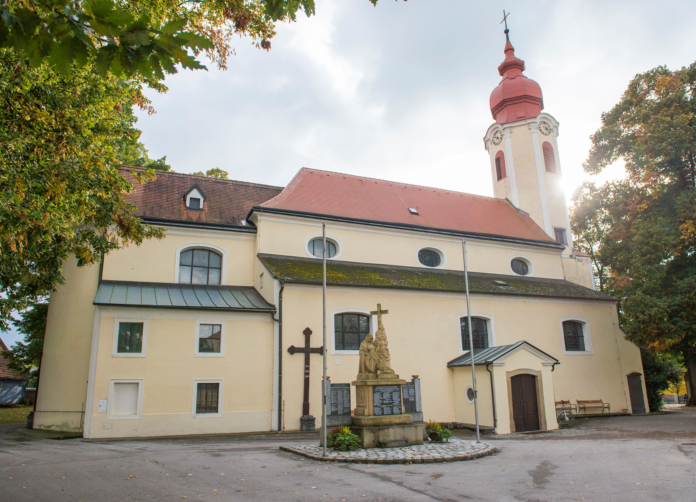 Farský kostol v Heiligeneichu so sochou a krížom v popredí.