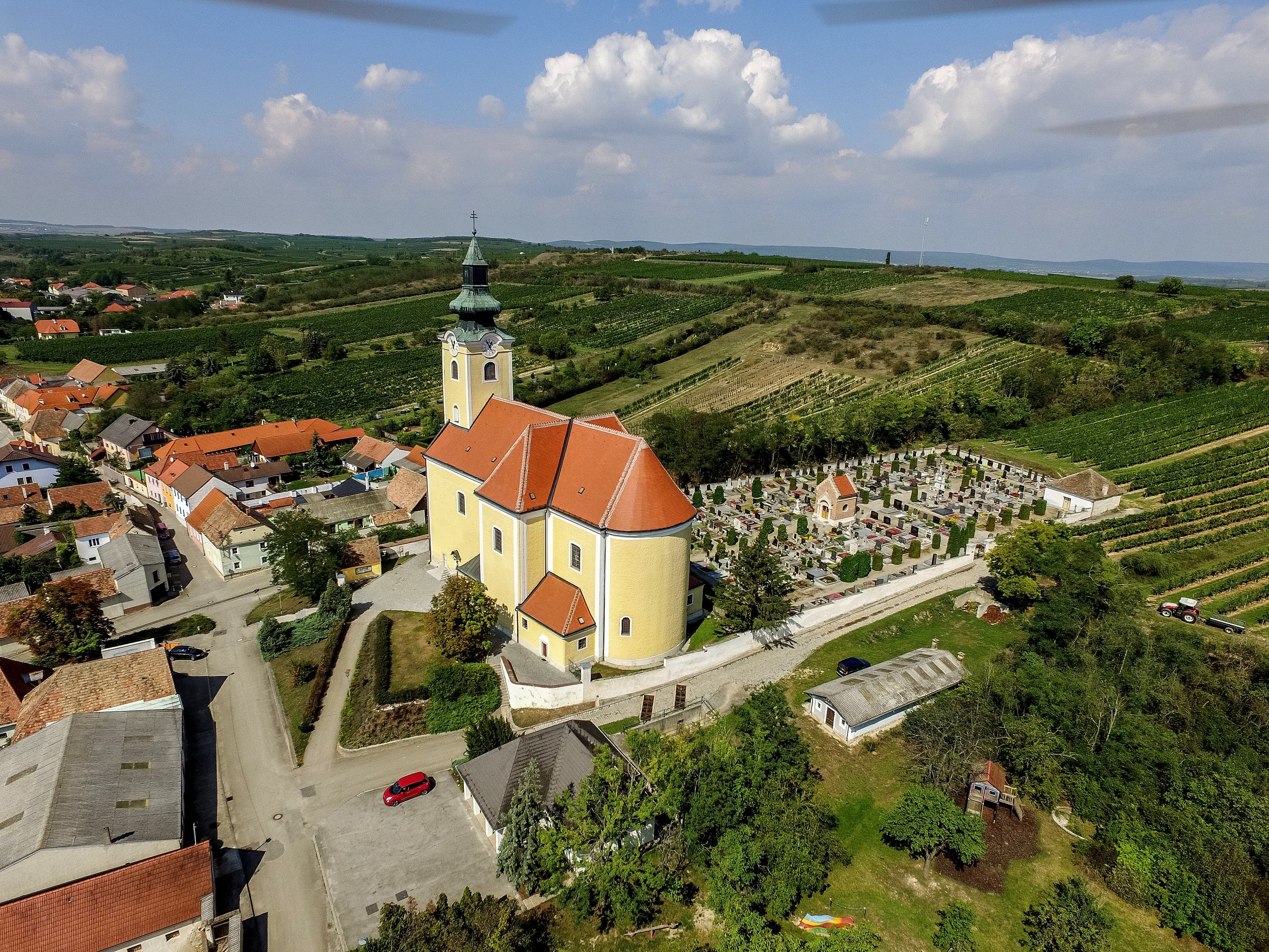 Letecký pohľad na farský kostol v Röschitzi s okolitým cintorínom a vinohradmi.