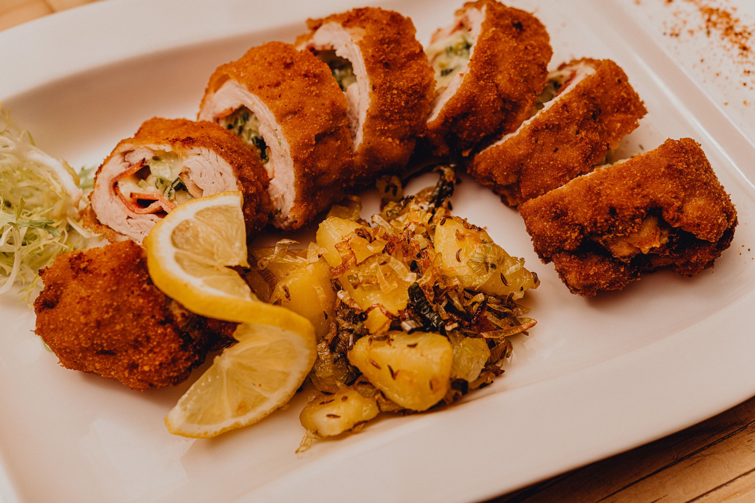 Plnené pečené morčacie filé so zemiakovou prílohou a plátkami citróna na bielom tanieri.