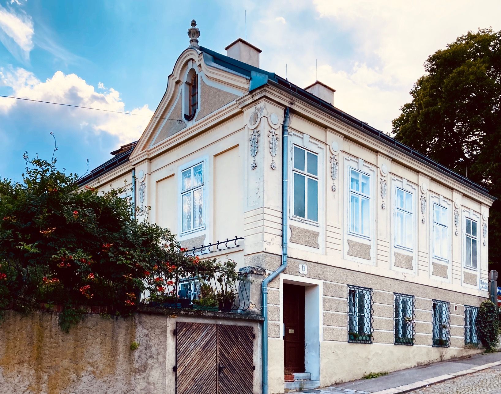 Pohľad zvonku na historickú vilu so zdobenými oknami a štítom.